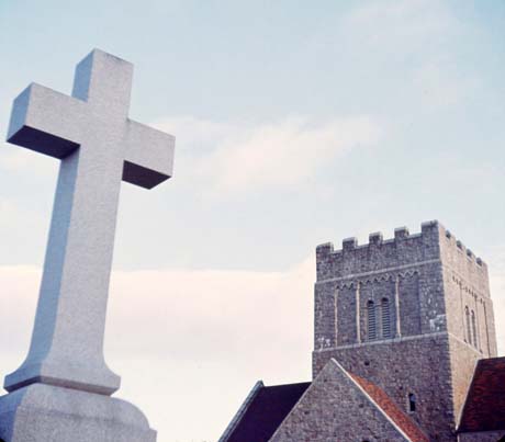 color photograph: cross with church in background