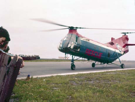 color photograph: helicopter w/blades reving up and airshow viewers behid fence
