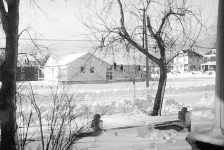 grayscale photograph: snow covered view of home constructin wrapup accross street