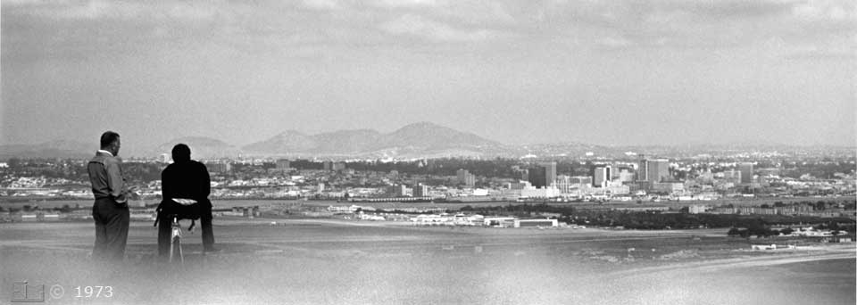B/W photo: Pedestrian and cyclist viewing San Diego skyline - Embedded text: 12/1972