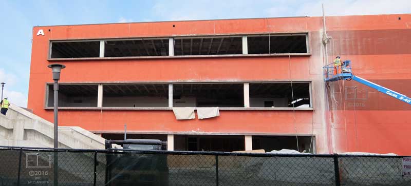Worker in cherry-picker working on face of "A" building shell - head-on view