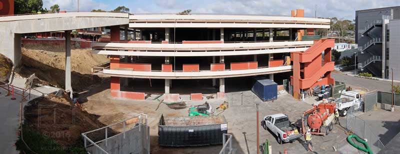 Wide, elevated, curvilinear view of "T" building with workers in foreground
