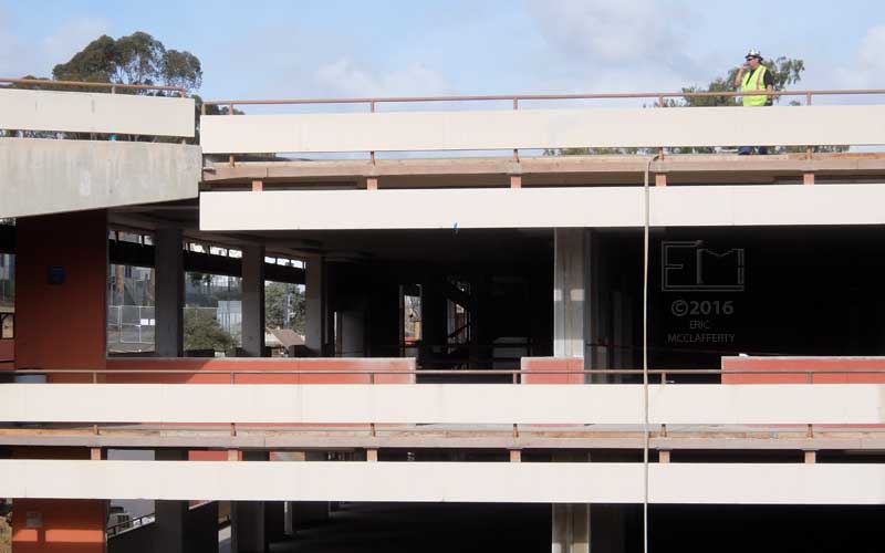 Construction worker on cell-phone atop four-walled "T" building