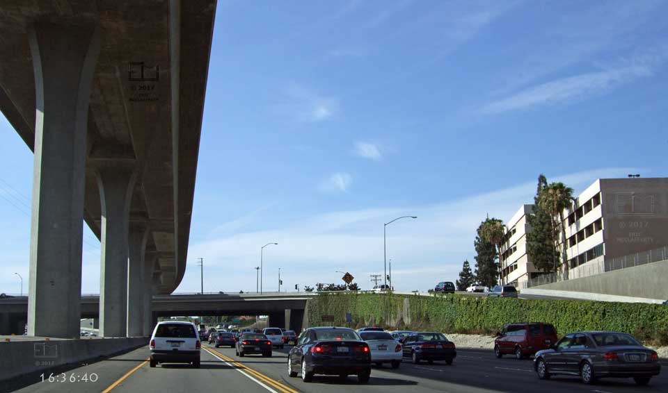 Timestamp 16:36:40 - Large building and freeway off ramp to I5 overpass on right - Supporting pillars and overhead freeway on left