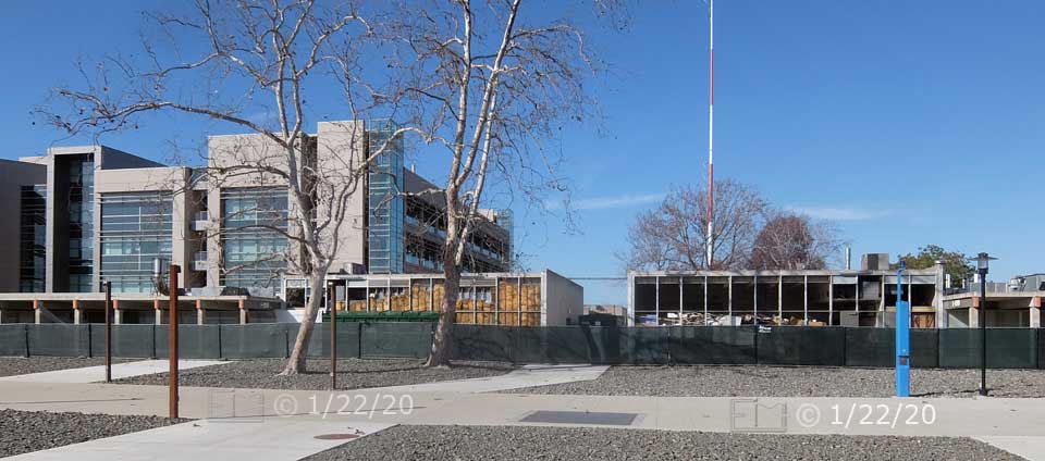 Concourse in foreground, buildings beyond fence