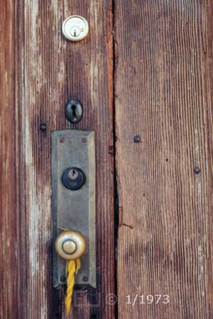 Color photo: Timeworn door with new, vintage, and antique locks - Embedded text: 11/23/72