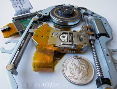 Color photo: Full deapth of field close up view of portable DVD disc drive mechinism  - Embedded text: 3/7/17
