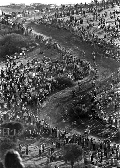 B/W photo: Wide view of multiple racers ascending curved racetrack up side of hill - Embedded text: 11/5/72
