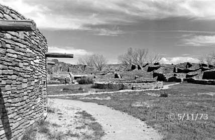B/W photo: View of ruins/central plaza while walking adjacent to Great Kiva - Embedded text: 5/11/73