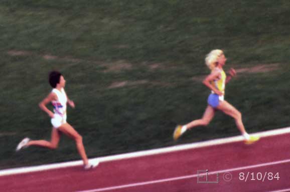 Color photo: Two runners (airborne?) with synchronous strides  - Embedded text: 8/10/84