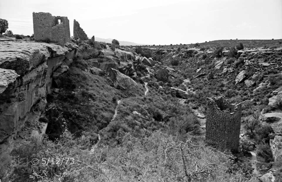 B/W photo: Ruins on mesa above square tower ruin in canyon below - Embedded text: 5/12/73