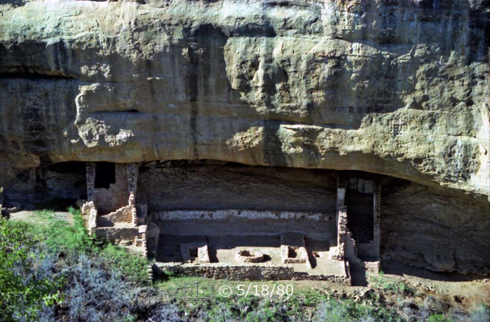 Color photo: Landscape view of Fire Temple Ruins and overhanging cliff from across canyon - Embedded text: 5/18/80
