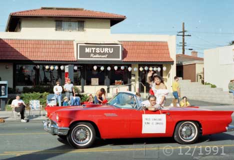 Color photo: Miss Lakeside waves to spectators from a red sports car convertible - Embedded text: 12/1991