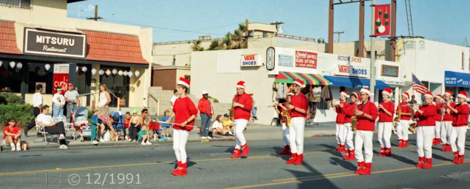 Color  photo: Red and white attired musicians advance along parade route - Embedded text: 12/1991