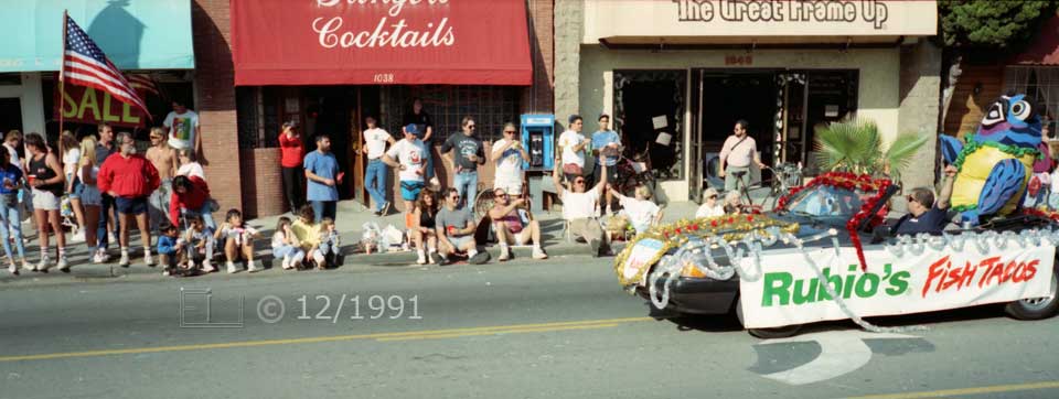Color photo: Rubio's Fish Tacos vehicle passing by curbside spectators - Embedded text: 12/1991