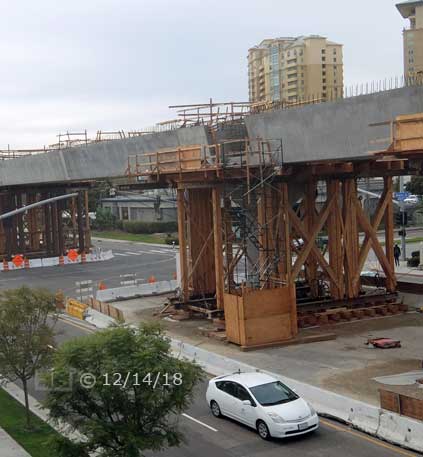 Color photo: Elevated view of trolley line construction at Genesee Ave/Esplanade Ct intersection - Embedded text: 12/14/18