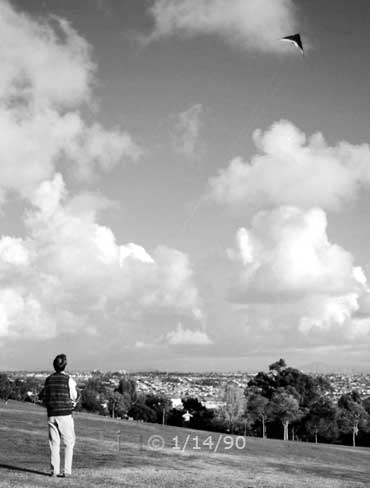 B/W photo: Kite flying in large, open area park - Embedded text: 1/14/90