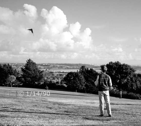 B/W photo: Kite flying in large, open area park - Embedded text: 1/14/90