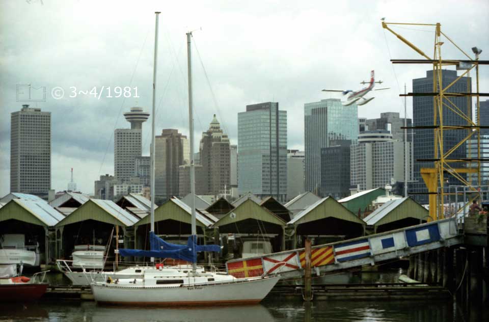 Color photo: A cluttered view of a marina with Vancouver high rise buildings as a backdrop and a seaplane about to land - Embedded text: 3~4/1981