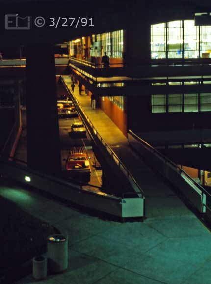 Color photo: Night-time view of 'T' building viewed from 'L' building - Embedded text: 3/27/91