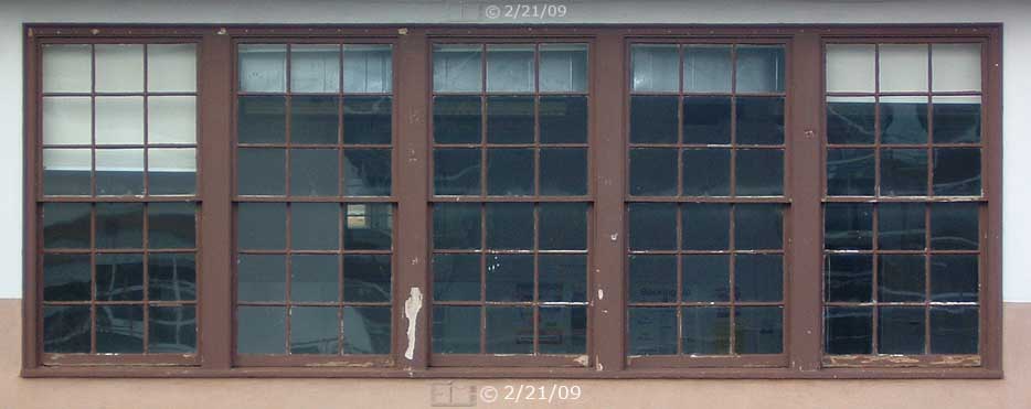 Color photo: Direct view of five window frames on west side of building- Embedded text: 2/21/09