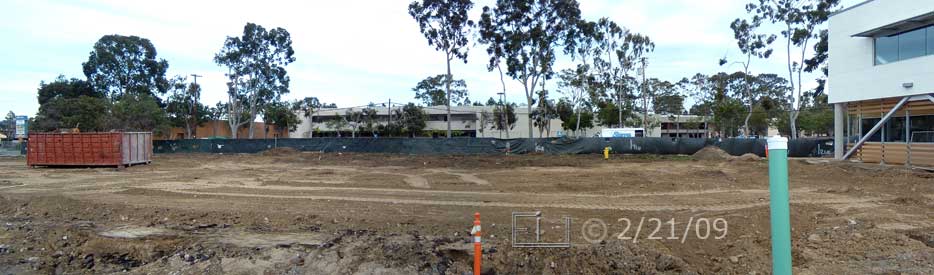 Color photo: Wide view looking south to open field where demolished building once stood; new building on right - Embedded text: 2/21/09