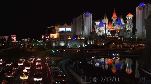 DSC color photo: Nighttime view of Las Vegas Blvd and Excalibur from pedestrian overpass, looking south  - Embedded text: 2/17/11