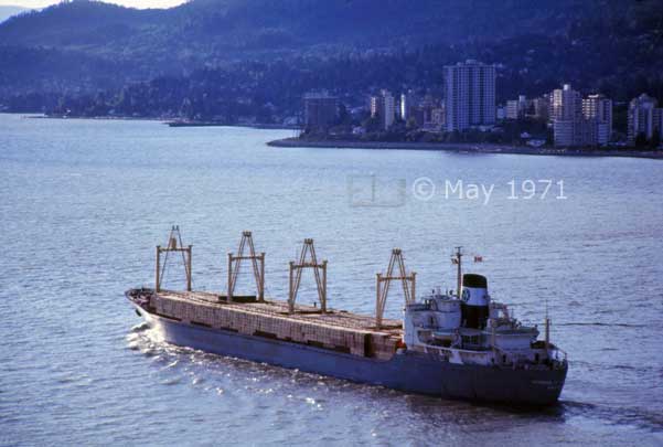 Color photo: Outgoing, loaded freighter on Burrard inlet with North Vancouver as backdrop - Embedded text: May 1971