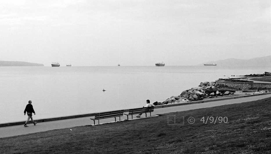 B/W photo: Walkway along shore of English Bay with freighters on horizon - Embedded text:4/9/90