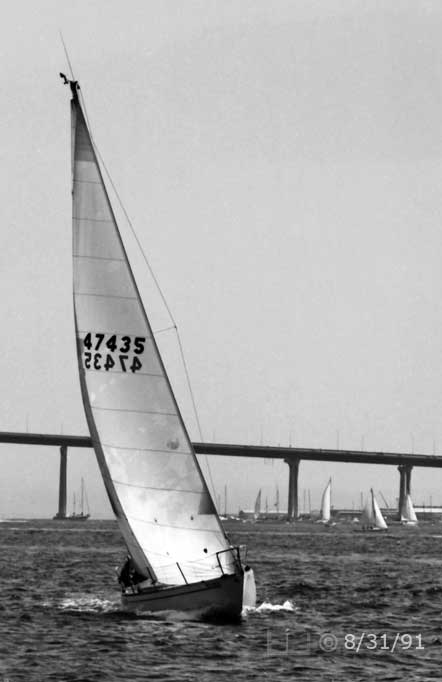 B/W photo: Bow view of boat under sail with Coronado Bridge in background - Embedded text: 8/31/91