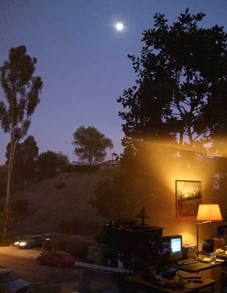 Color photo: Livingroom reflected on window which views a dark twilight scene outside